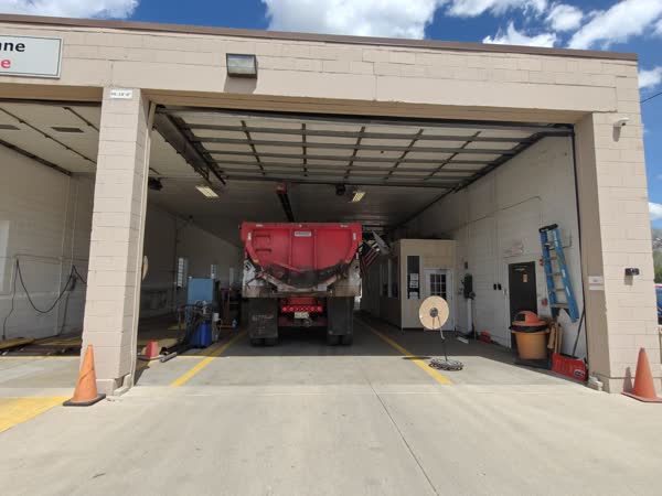 Red dump truck being inspected inside the drive-through bay.